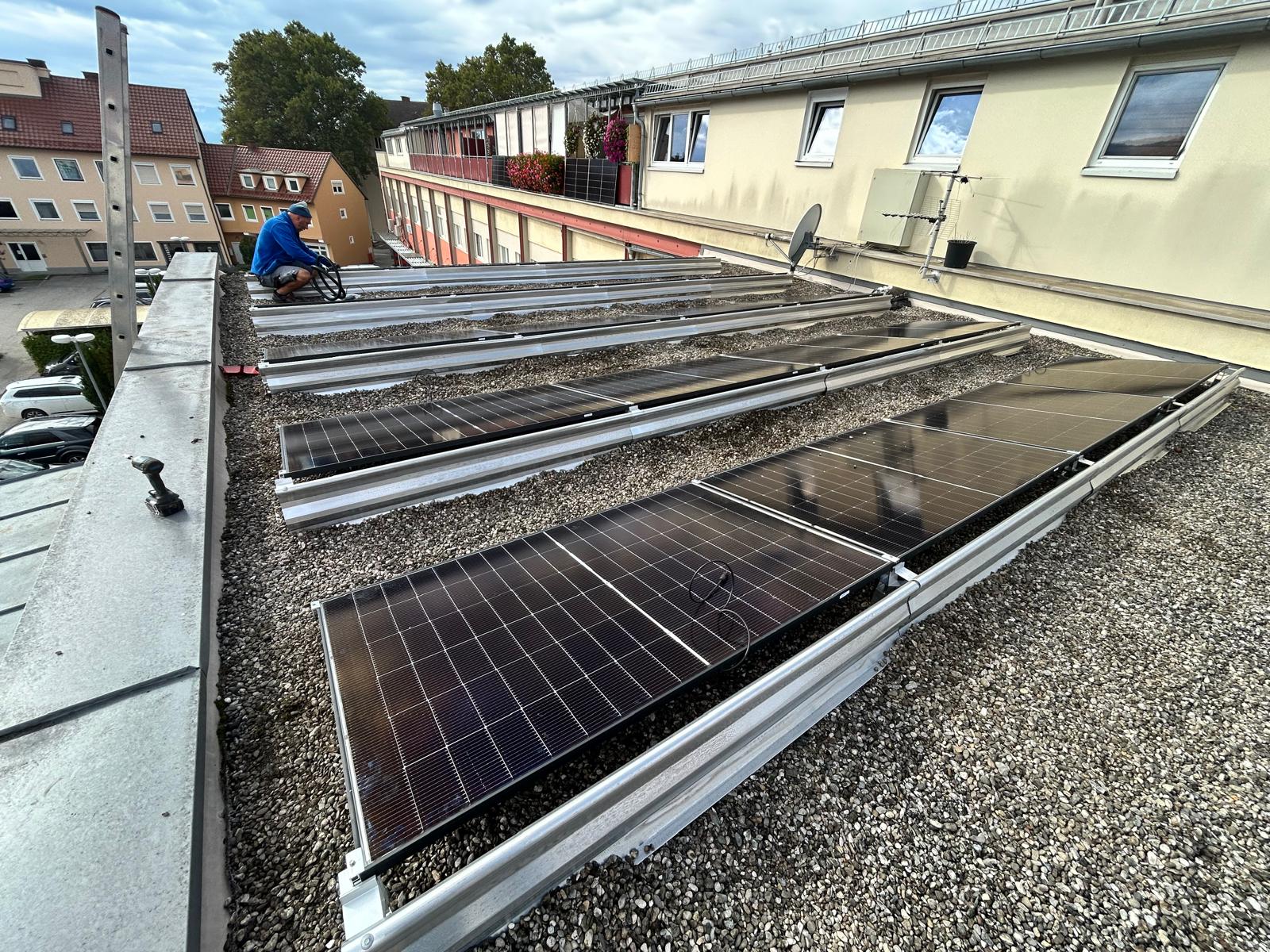 Kompakte Solaranlage auf Flachdach eines Privathauses, aufgeständerte Module auf Kiesdach